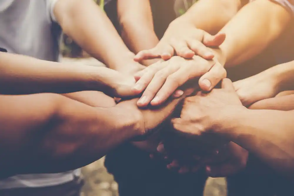 Un primo piano di pi&ugrave; mani impilate l'una sull'altra, a simboleggiare il lavoro di squadra e l'unit&agrave;.