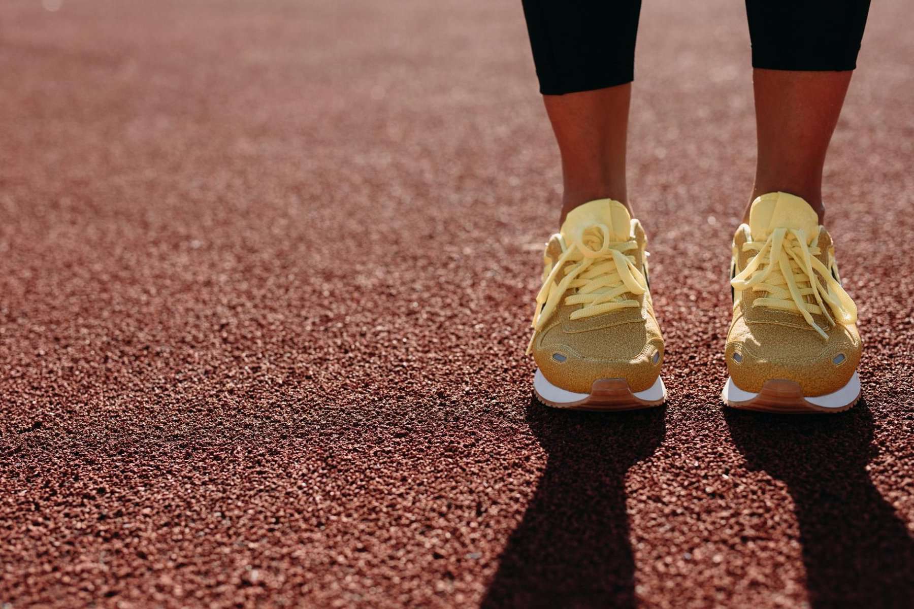 Una donna con scarpe da corsa gialle in piedi su una pista.