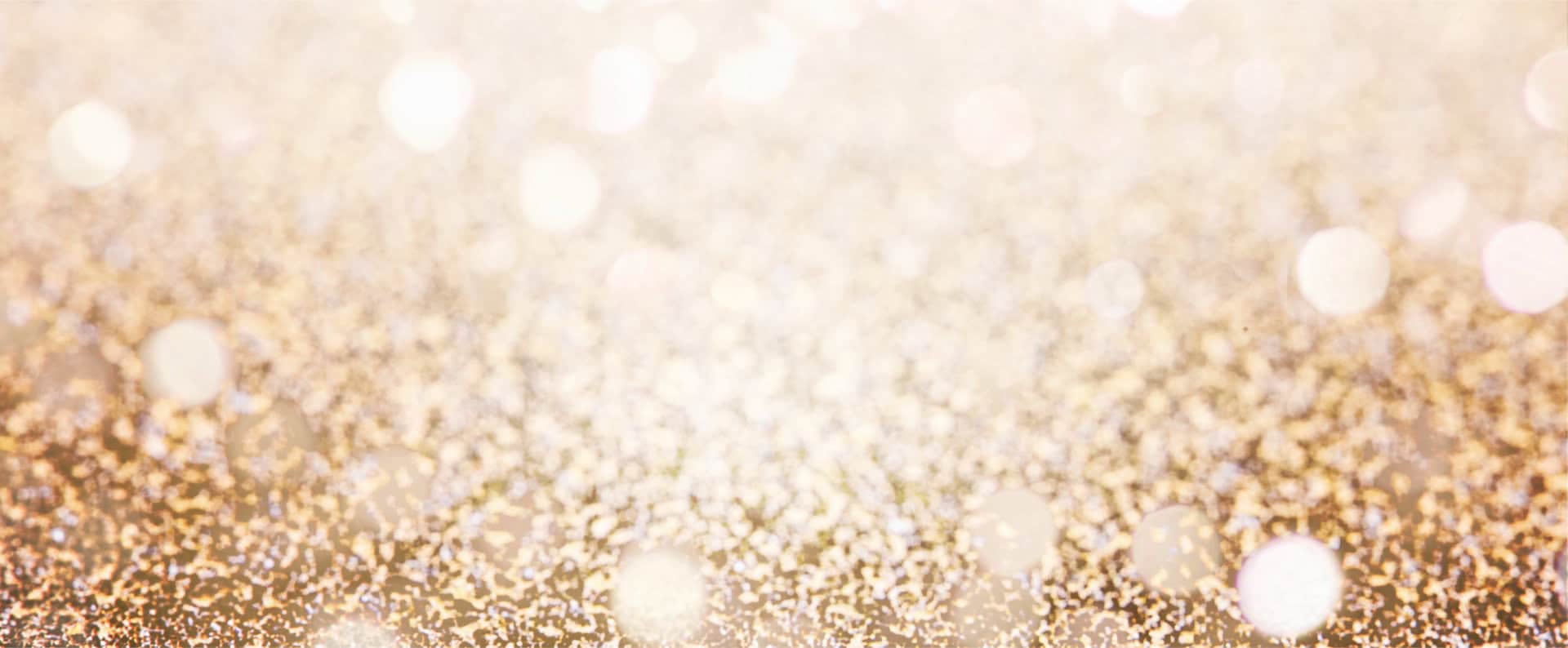 Uno sfondo sfocato con glitter dorati e punti luce sfocati che creano un effetto scintillante.